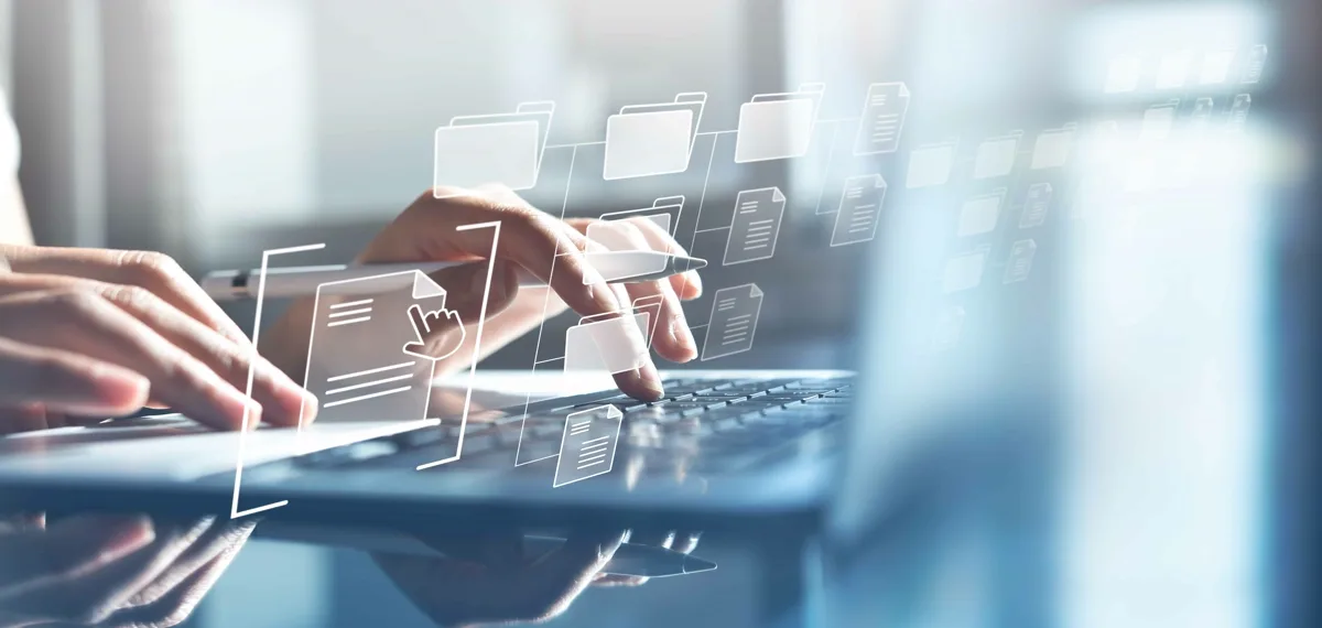 Closeup of a person's hands typing on a laptop. They are holding a pen in one hand as they do and there is a translucent overlay of file icons, representing Usenet retention.
