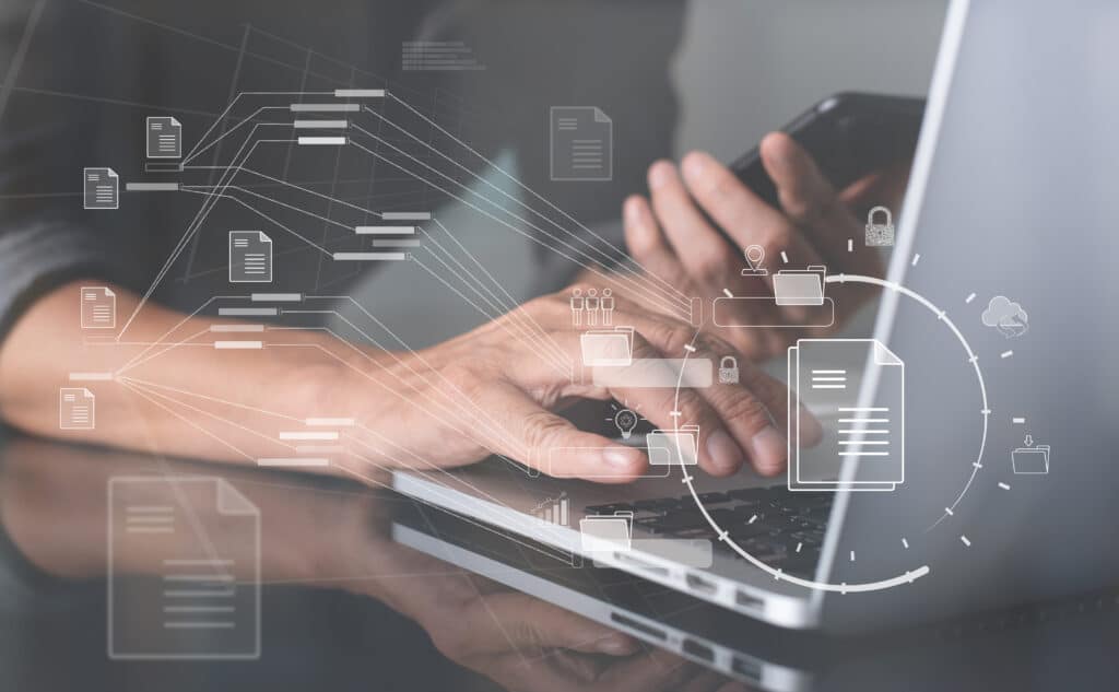 Premium Usenet Retention. Closeup of a pair of hands. One is holding a cellphone and the other is typing on a laptop.